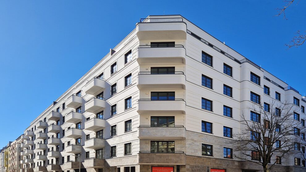 Auf dem Bild ist ein Aufzug von Ammann & Rottkord GmbH zu sehen. Dieser ist weiß und steht neben einem schwarzen Treppenhaus.