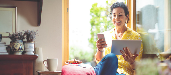 Eine Frau zuhause mit Smartphone und Tablet