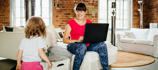 Eine Frau mit Kind arbeitet an einem Laptop