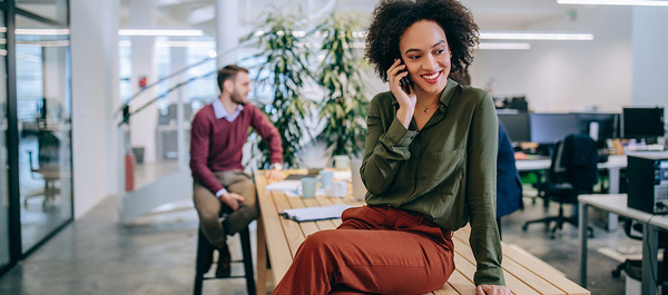 Eine Frau mit Handy telefoniert im Büro