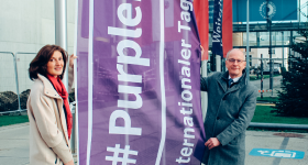 Bild zeigt Rektor und Behindertenbeauftrage mit der Fahne zur Kampagne #PurpleLightUp