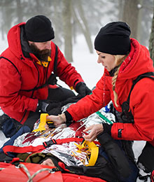 Zwei Bergretter versorgen eine verunfallte Person. Foto: Halfpoint/stock.adobe.com.