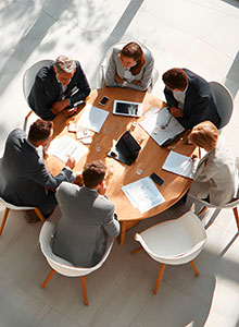 Mehrere Personen sitzen während einer Besprechung an einem Tisch. Foto: Moritz/stock.adobe.com, KI-Bild.
