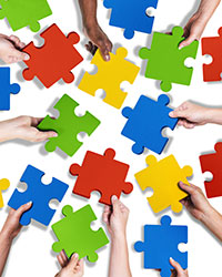 Detailaufnahme von mehreren Händen mit Puzzleteilen. Foto: Rawpixel.com/Shutterstock.com.