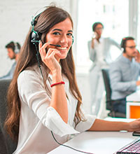Eine Dame mit Headset sitzt an ihrem Arbeitsplatz.