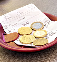 Einige Euro-Münzen liegen auf einer Rechnung. Foto: Image'in/stock.adobe.com.