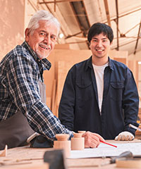 Ein älterer Arbeiter mit einem jungen Mann in einer Werkstatt. Foto: Robert Kneschke/Shutterstock.com.
