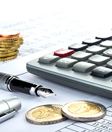 Detailansicht eines Taschenrechners, von Münzen und Füllfeder. Foto: v.poth/stock.adobe.com.