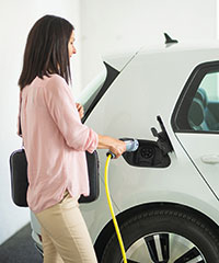 Eine Frau beim Laden ihres Elektroautos. Foto: husjur02/Shutterstock.com.