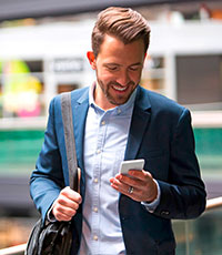 Mann mit Tasche blickt auf sein Smartphone. Foto: Production Perig/Shutterstock.com.