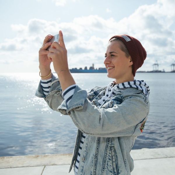 Junge, lächelnde Frau fotografiert sich selbst mit dem Handy