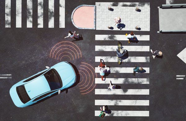 A car with sensor signals approaches a zebra crossing where pedestrians and cyclists are crossing the road.