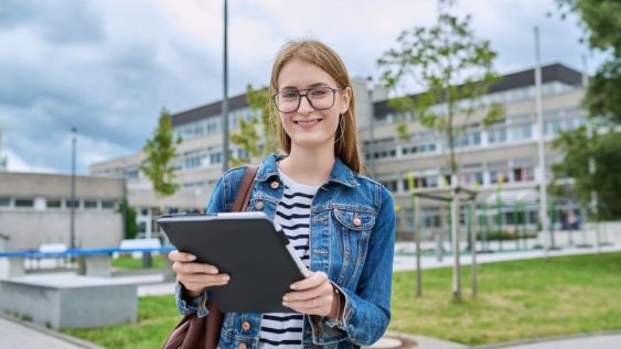 A woman holding a folder, standing outside of a large building