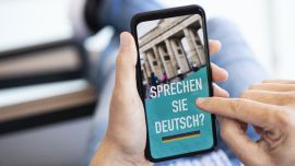 A person scrolling through a phone with the sentence “Sprechen Sie Deutsch?” shown on the screen