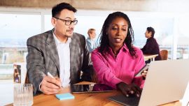 A man and a woman sitting next to each other in front of a laptop
