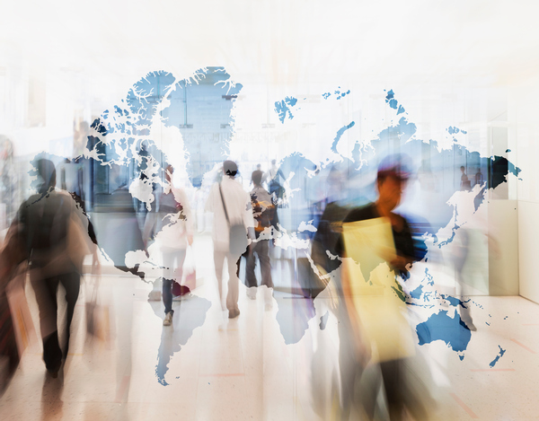 A transparent map of the world with blurry people walking in the background.