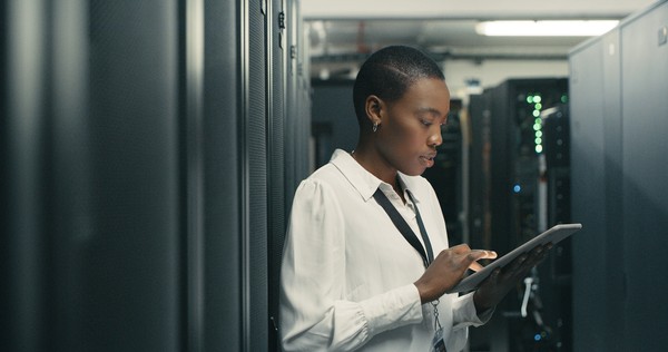 A woman in a server room with a tablet in her hand.