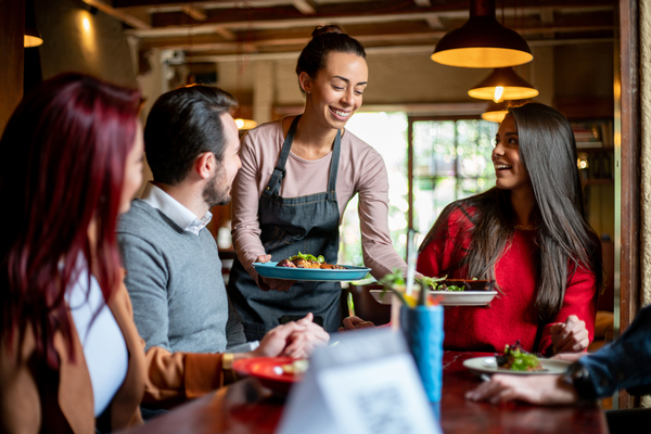 Waitress serving food to smiling diners in a restaurant
