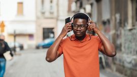 A young man on the street putting on headphones