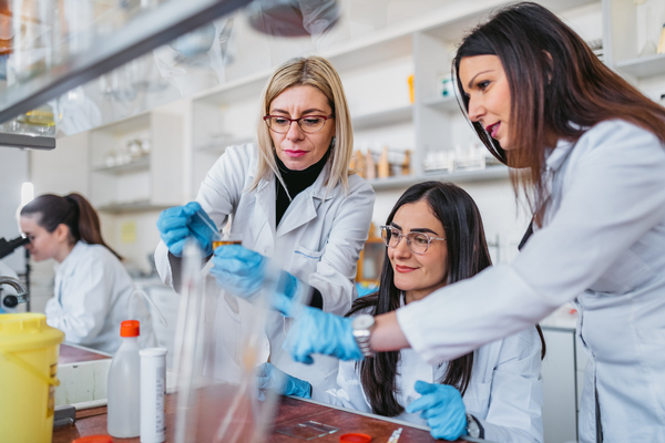 Three women in lab coats working together in a laboratory