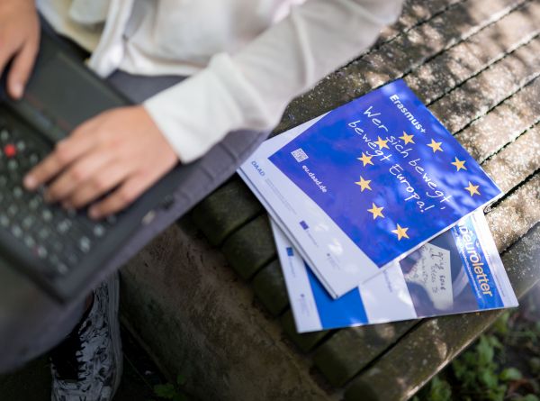 Neben einer Person mit Laptop auf dem Schoß liegen Broschüren auf einer Bank. Die Aufschrift "Wer sich bewegt, bewegt Europa!" ist zu erkennen.