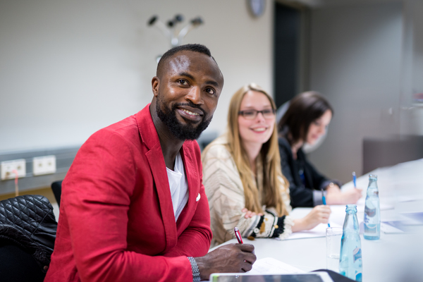 Eine Gruppe junger Erwachsener steht auf einer Bühne und applaudiert gemeinsam mit dem Publikum. Hinter der Bühne ist auf einer Leinweinwand ein Leuchtturm und der Schriftzug "Science Show" zu erkennen.