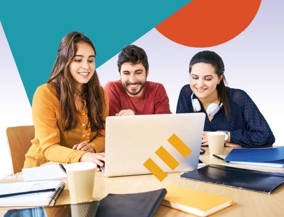 Drei junge Erwachsene sitzen an einem Tisch und schauen gemeinsam lächelnd auf einen Laptop. Auf dem Tisch stehen Kaffeebecher und es liegen verstreut Notizblöcke, Hefte, Ordner und Stifte.