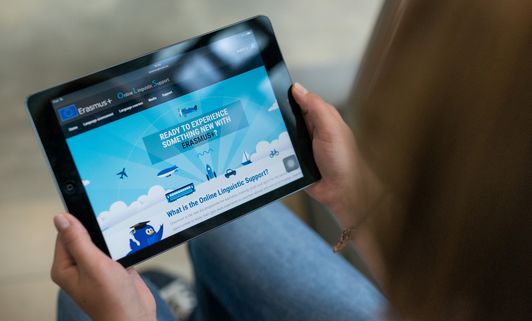 Nahaufnahme eines Tablets, welches von einer Frau mit beiden Händen gehalten wird.