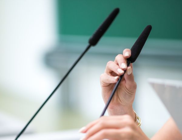 Nahaufnahme zweier Hände, die ein Hörsaal-Mikrophon ausrichten.