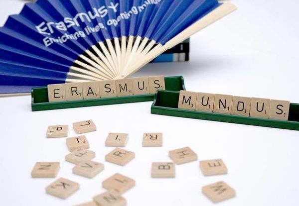 Auf einem weißen Tisch liegen einige Buchstabensteine eines Wortlegespieles. Auf zwei Ablageleisten sind die Worte "Erasmus" und "Mundus" zu lesen.