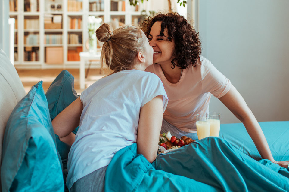 Zwei Frauen im Bett beim Fruehstueck